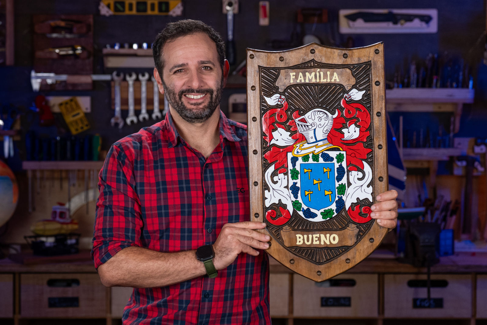 Iberê Thenório, criador do Manual do Mundo, segurando um brasão de família entalhado pela Pica-pau Entalhes